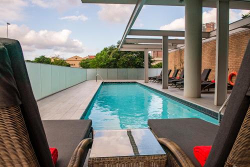 una piscina en la azotea con sillas y una piscina en ONOMO Hotel Durban en Durban