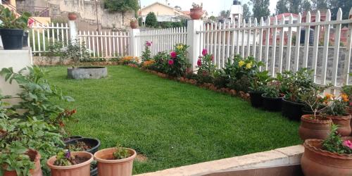 um jardim com vasos de plantas e uma cerca branca em Aanvis inn em Ooty