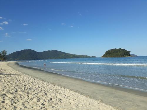 uma praia de areia com vista para o oceano em Casas em Condomínio próximo da praia com 2 dormitórios, churrasqueira e 3 vagas de garagem em Ubatuba