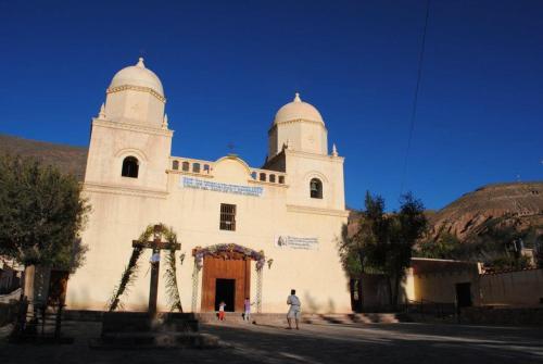 Une église blanche avec un homme debout devant elle dans l'établissement Alojamiento El Cardon Tilcara, à Tilcara