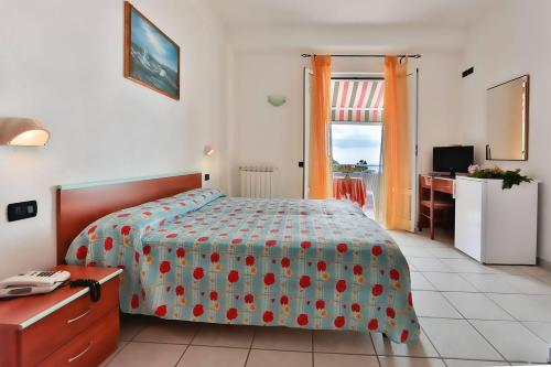 een slaapkamer met een bed, een bureau en een raam bij Hotel Villa Rita in Ischia