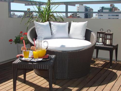 a wicker chair on a balcony with two tables with drinks at Zoom Apartments Hotel in Cordoba