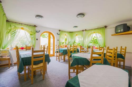 um restaurante com mesas e cadeiras com toalhas de mesa verdes em Babi Guesthouse - Babi Vendégház em Balatonfüred