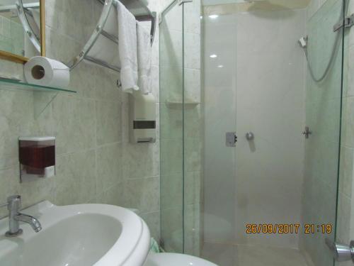 ein Bad mit einer Dusche, einem Waschbecken und einem WC in der Unterkunft Rizzo Plaza Hotel in Tumbes