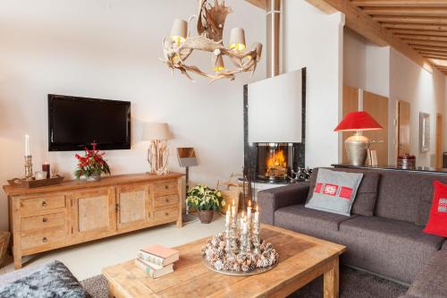 ein Wohnzimmer mit einem Sofa und einem TV in der Unterkunft Vrony Apartments by Hotel Walliserhof Zermatt in Zermatt