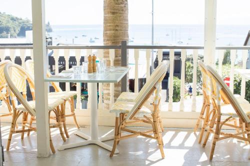 een tafel en stoelen op een balkon met uitzicht op de oceaan bij The Oyster Inn in Oneroa