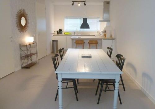 a kitchen with a white table and chairs in a room at Retro farmhouse Cadzand, Koolse Hoeve 1H in Cadzand