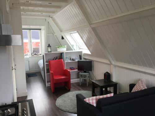 - un salon avec une chaise rouge et un bureau dans l'établissement B&B Alkmaars Toppunt, à Alkmaar