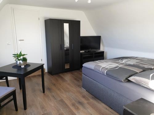 een slaapkamer met een bed, een tafel en een televisie bij Ferienwohnung Berger Bocholt in Bocholt