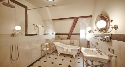 La salle de bains est pourvue d'une baignoire, d'un lavabo et d'un miroir. dans l'établissement Hotel Schloss Freudental, à Allensbach