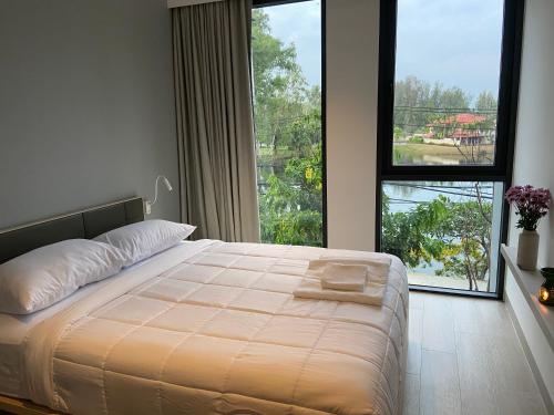 - une chambre avec un lit et une grande fenêtre dans l'établissement Cassia Apartment 1, à Bang Tao Beach