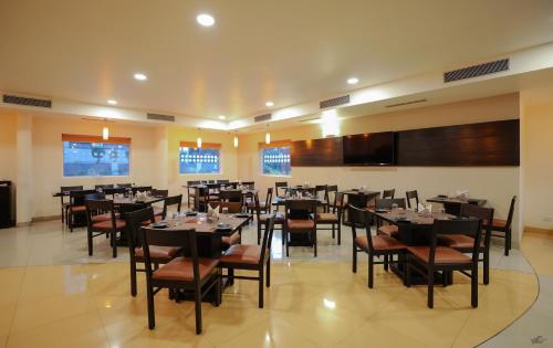 a dining room with tables and chairs and a tv at Ginger Nashik in Nashik