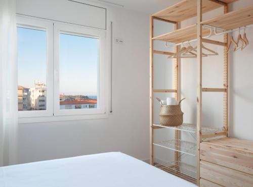 a bedroom with a bed and a book shelf and a window at LA CALA BEACH DELUXE Apartments in L'Ametlla de Mar