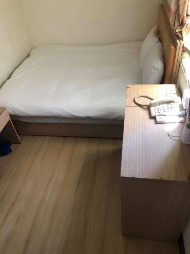 1 dormitorio con 1 cama y escritorio con teléfono en Huaxin Hotel en Jincheng