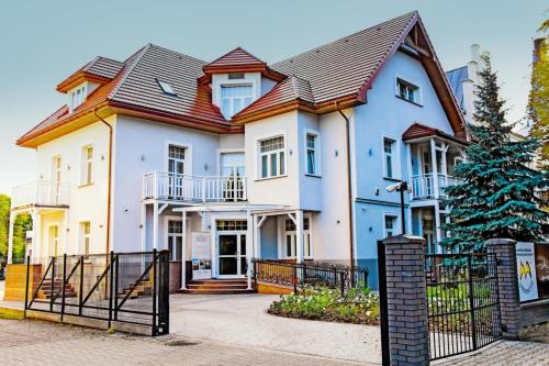 een groot wit huis met een metalen dak bij Willa Home in Ciechocinek