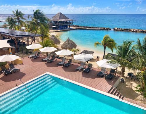 uma vista superior de uma piscina com guarda-sóis e do oceano em Curacao Avila Beach Hotel em Willemstad