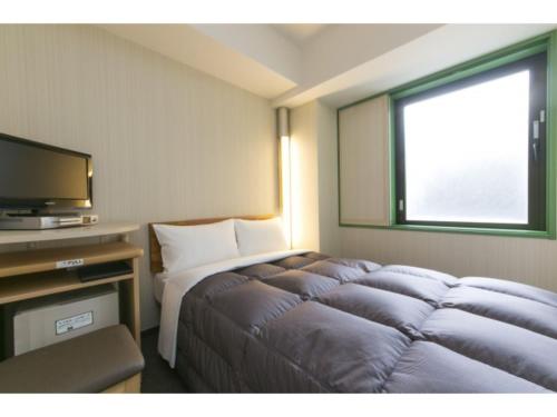 une chambre d'hôtel avec un lit et une télévision dans l'établissement R&B Hotel Shin Yokohama Ekimae - Vacation STAY 14694v, à Yokohama