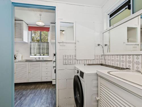 a white kitchen with a sink and a washing machine at Blueys Beach Villa Manyana 11 in Blueys Beach