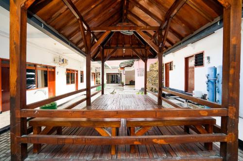 eine hölzerne Veranda mit einer Bank in einem Gebäude in der Unterkunft Merapi Inn Syariah by ecommerceloka in Surabaya