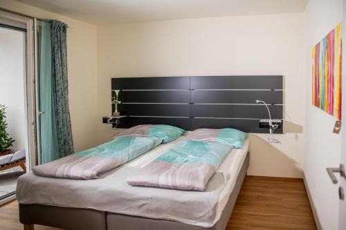 una camera con un grande letto con testiera nera di Cityapartment Dornbirn 50 qm a Dornbirn