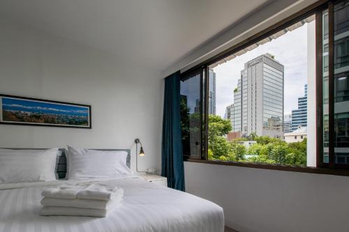 een slaapkamer met een wit bed en een groot raam bij Every Surawong in Bangkok