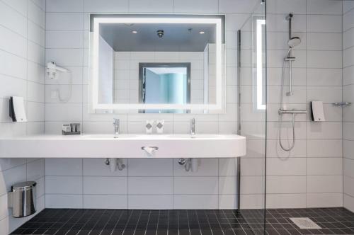 bagno bianco con lavandino e specchio di Thon Hotel Cecil a Oslo