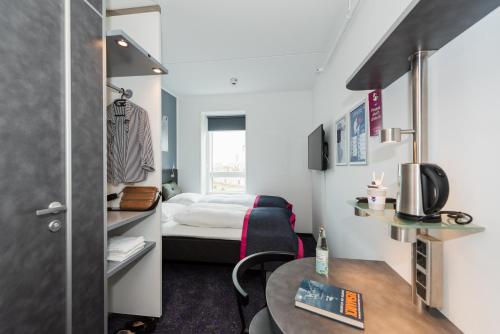 een kleine kamer met een bed en een tafel bij Cabinn Copenhagen in Kopenhagen