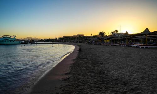 a beach with a boat in the water at Andalusia Blue Beach Hurghada in Hurghada