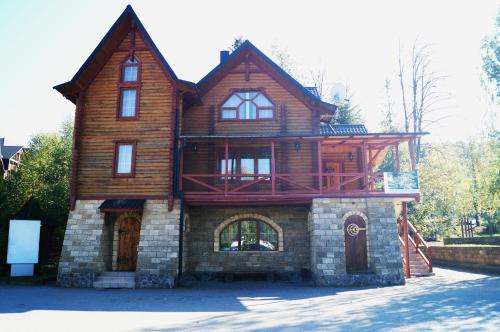 una grande casa in legno con un portico in cima di Норіс a Myhove