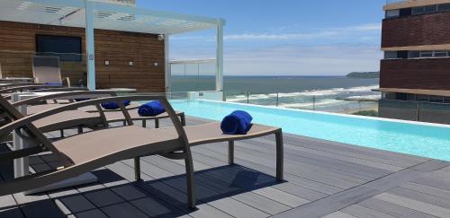 un complejo con una piscina con sillas y el océano en Blue Waters Hotel en Durban