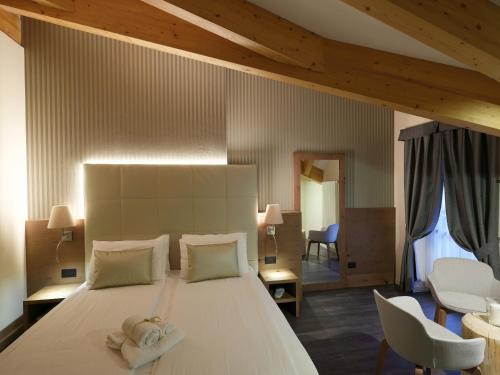 - une chambre avec un grand lit blanc et 2 serviettes dans l'établissement X Alp Hotel, à Pozza di Fassa