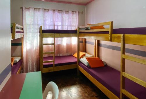 バギオにあるRedDoorz Hostel MRC Residences Baguioの二段ベッド3組とテーブルが備わる客室です。