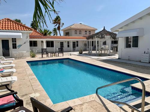 una piscina con sillas y una casa en Tu Casita en Aruba en Palm-Eagle Beach