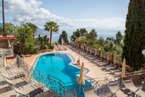 a swimming pool with lounge chairs and a resort at Hotel Ariston and Palazzo Santa Caterina in Taormina