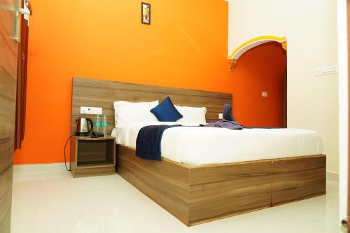 1 dormitorio con 1 cama con pared de color naranja en NJK Residency en Yercaud