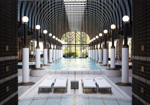 una piscina in un edificio con tavoli e sedie bianchi di Victoria Jungfrau Grand Hotel & Spa a Interlaken