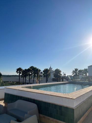 uma piscina com cadeiras e palmeiras em Hotel La Malvasía em El Rocio