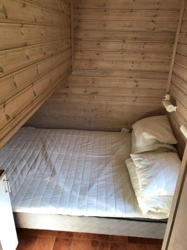 een bed in een kamer met een houten muur bij Stockholm Swecamp Flottsbro in Huddinge