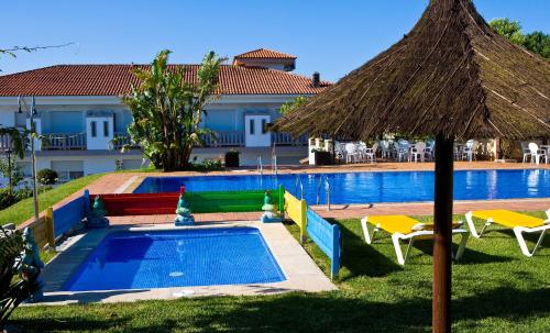 una piscina con sombrilla y sillas y un edificio en Aparthotel Cabicastro en Portonovo