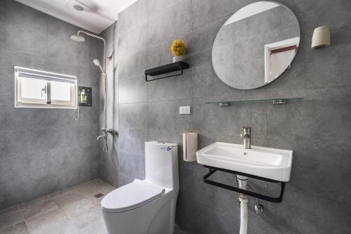 a bathroom with a toilet and a sink and a mirror at Hibnb Guesthouse in Zhuangwei