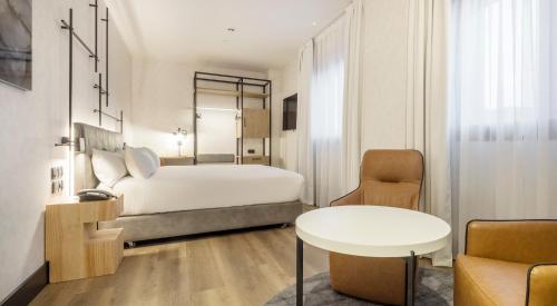 um quarto com uma cama, uma mesa e uma cadeira em Hotel Ilunion San Mamés em Bilbao