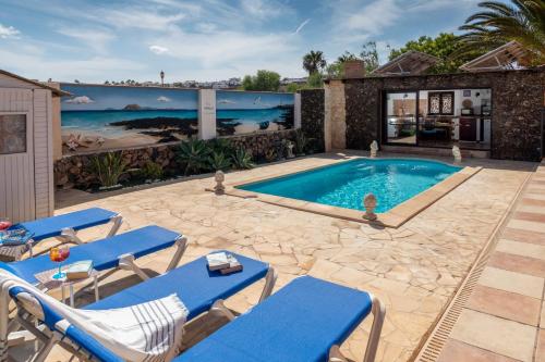 een zwembad met blauwe ligstoelen en een huis bij Villa Maravilla piscina climatizada in Villaverde