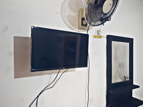 a flat screen tv sitting on a wall next to a fan at Cozy Homestay Waterfall Road Ella in Ella