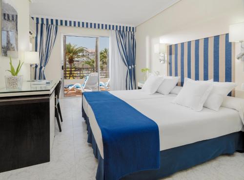 um quarto de hotel com uma cama grande e uma varanda em H10 Las Palmeras em Playa de las Americas