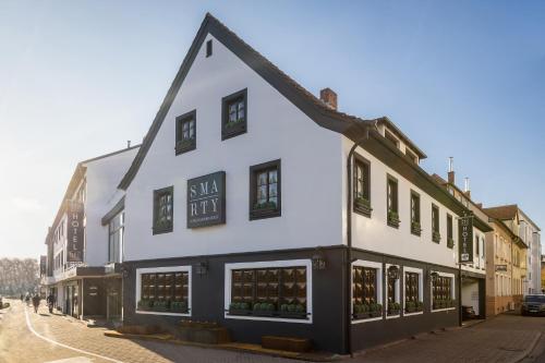 un bâtiment blanc avec des parures noires dans une rue dans l'établissement SMARTY Hotel Euler Homburg, Saar - KONTAKTLOSER SELF CHECK-IN, à Hombourg