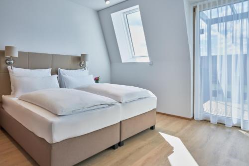 um quarto com uma grande cama branca e uma janela em Aparthotel Bad Radkersburg em Bad Radkersburg