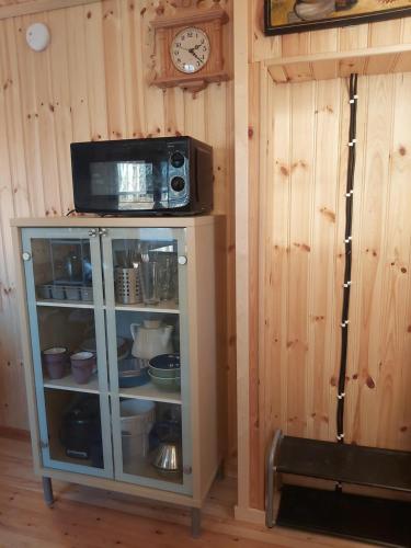 een kast met een magnetron en een klok aan een muur bij Countrycabin Bergslagen stuga in Ramsberg