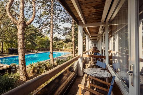 een veranda met een tafel en stoelen en een zwembad bij Badhotel Rockanje in Rockanje