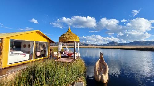 普諾的住宿－Uros Lodge Perú，河边的黄色房子,设有凉亭