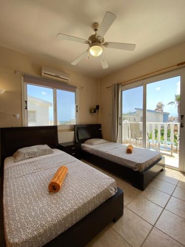 1 dormitorio con 2 camas y ventilador de techo en Sea View Villa in Agia Thekla, en Ayia Napa